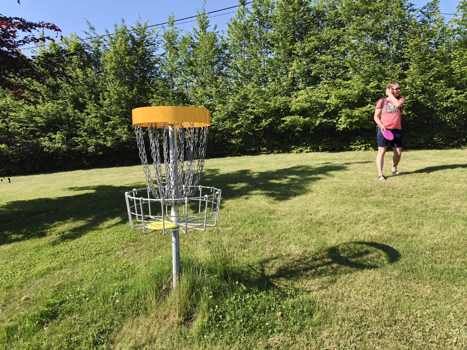 Discgolfový koš a hráč na hřišti