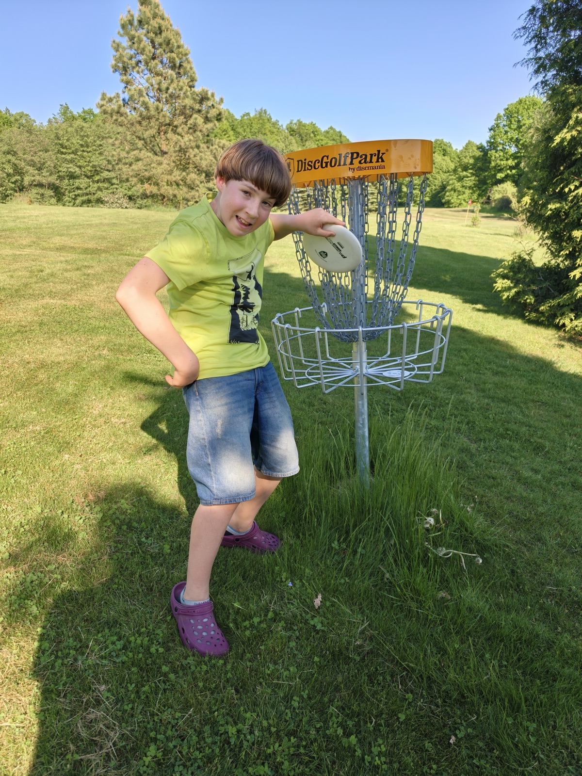 Mladý hráč s diskem u certifikovaného discgolfového koše